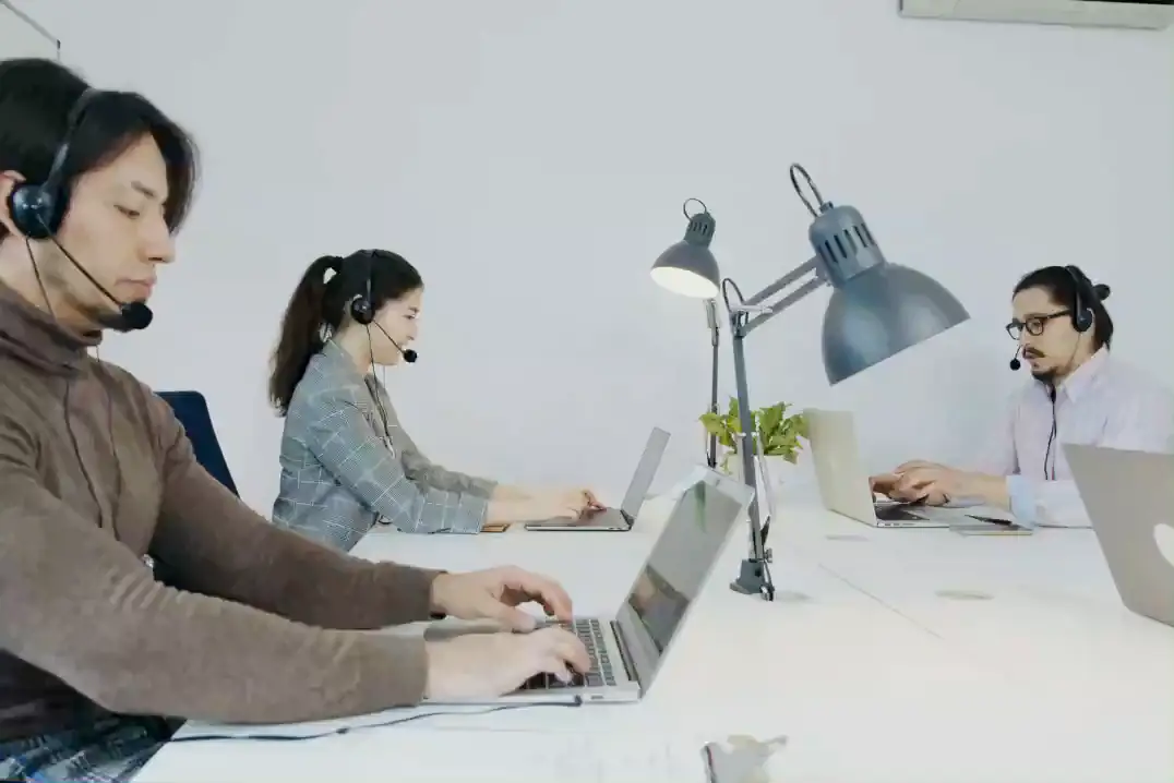 Callcenter-Team arbeitet mit Headsets an Laptops