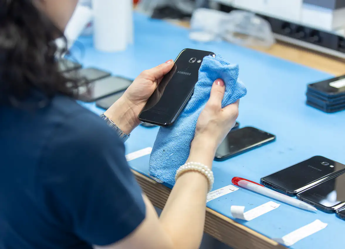 Employee cleaning a refurbished smartphone
